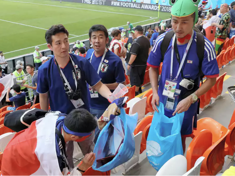 Japan fans clean up the stadium after they won the match